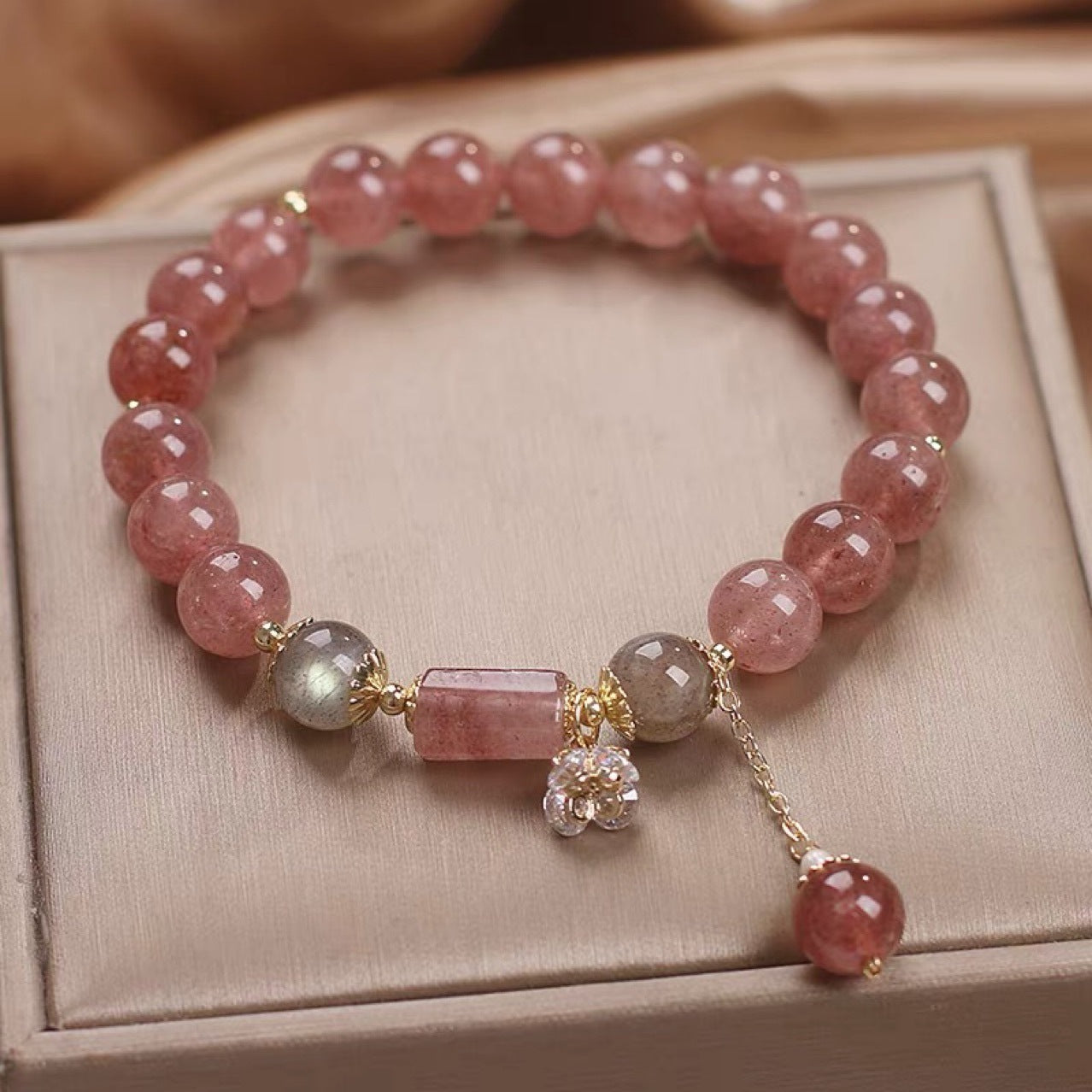 Natural strawberry quartz bracelet with zircon flower accents on white background